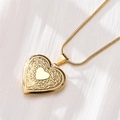 Macro view of golden heart locket necklace with floral engraving on white textured fabric - Intertwined Floral Relief