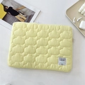 Detail of light yellow quilted laptop sleeve featuring soft cloud patterns and woven label - 11" / Yellow