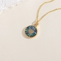 Détail d'un collier doré avec mosaïque de nacre bleue et zircon en forme de cœur brillant - Coloré