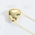 Dettaglio ravvicinato di un ciondolo a cuore 3D dorato su uno sfondo bianco pulito e puro - Cuore Grande / Oro