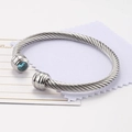 Silver twisted cable open bangle featuring a round blue zircon gemstone at the end - December / Blue Green