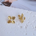 Macro detail of gold flower earrings with brushed texture and center pearls on stone - Stud Earrings