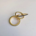 Three minimalist gold interlocking rings with small blue gemstones on a white base - Spec 2 (Blue Gemstone)