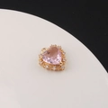 Détail macro d'un pendentif cœur doré avec un grand zircon rose et des pierres claires - Rose