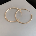 Close-up of high-polish large golden hoop earrings with minimalist circular design - 6cm / Gold / Silver Needle