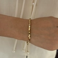 Detalle de una pulsera minimalista de acero inoxidable con cubos dorados en la muñeca - Estilo Cuadrado en Forma de Cubo (B280) / Dorado