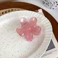 Close-up of a translucent pink flower hair claw clip on a stylish decorative tray - Pink