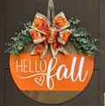 Round wooden door sign with Hello Fall text, pumpkin bow and green leaves on dark door - HELLO Pumpkin Green Leaf Sign
