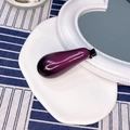 Detailed view of creative purple eggplant hair clip on white ceramic plate background - Eggplant