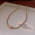Dettaglio della collana dorata con ciondolo cilindrico floreale e cordino in pelle nera - Collana - Oro (Piccolo)