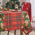 Detalle del mantel navideño de cuadros rojos con hojas de acebo y casa de jengibre - Cuadros de Navidad