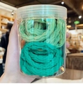 Detail view of green gradient threaded hair ties in a clear cylindrical storage jar - Green Threaded Rings 30 Pieces/barrel