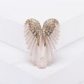 Elegant gold angel wing brooch with white enamel and sparkling rhinestones on a white stand - White