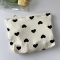 Vista detallada de neceser de lona crema con estampado de corazones y relieve - Neceser de maquillaje / Corazón Negro