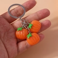 Dettaglio portachiavi in metallo argento con tre piccoli ciondoli a forma di zucca arancione - Zucca