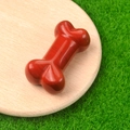 Polished red natural agate bone-shaped carved stone miniature on a wooden base - Red Jasper