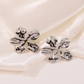 Elegant silver flower stud earrings with hammered metal texture on white satin background - Silver