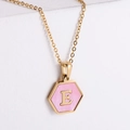 Vue macro du pendentif hexagonal doré 18k avec incrustation de nacre rose et lettre E - Or-E
