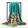 Présentation artistique d'un foulard en soie vert à motifs floraux oranges - Yimei-Bleu Paon