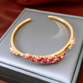 Detalle macro del brazalete de onda en oro de 18k con piedras rojas y rosas en seda - Dorado Rosa Púrpura