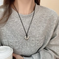 Close-up of a vintage hollow heart pendant necklace with a black cord on a model - Silver Hollow Heart with Black Cord