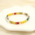 Detail of colorful bohemian stacked beads on a white ceramic tray with soft lighting - Multicolor Style-J
