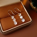 Detailed view of silver hook earrings with three zircon stones in a velvet jewelry box - Silver