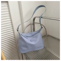 Light blue fabric shoulder bag with zipper closure on a modern minimalist shelf - Blue