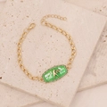 Gold Libra zodiac bracelet with green enamel and zircons on a natural stone background - Libra