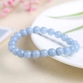 Elastic beaded bracelet with light blue semi-transparent round stones on white ceramic plate - Synthetic Aquamarine