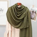 Detail of a dark green linen scarf with natural texture styled on a beige trench coat - Army Green