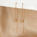 Detalle de pendientes largos dorados con cuentas pulidas y cadenas de borlas elegantes - Oro rosa