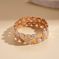Dettaglio macro del bracciale elastico vintage dorato con smalto bianco e strass - Bianco