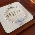 Makroaufnahme des Schmetterling-Perlenarmbands mit blauen Kristallen auf Holzschmucktablett - Armband + Ohrstecker Set (Silber/Weiß/Blau)