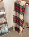 Dettaglio di sciarpa tartan rossa e beige con frange, appoggiata su una sedia bianca - Stile Nappa di Natale / 160x70cm / Scozzese Rosso Verde