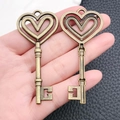 Due ciondoli vintage in bronzo a forma di cuore per collane tenuti in mano per misura - Chiave a Cuore in Bronzo Antico 31x70mm