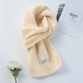 Soft beige knitted scarf with minimalist logo tag on a clean aesthetic background - Yellow Beige