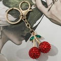 Portachiavi ciliegia di lusso con strass rossi e metallo dorato su sfondo rivista moda - Stile Foglia con Strass Rossi (KC2018)