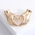 Elegante goudkleurige metalen broche met handen in hartvorm voor jassen - Goud