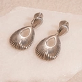 Close-up of silver teardrop hollow earrings with radiant texture on stone background - Ear Clip - Silver