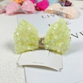 Macro detail of yellow sequin mermaid bow hair clip with gold glitter center on card - Sequin Fluorescent Yellow