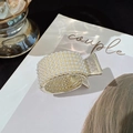 Elegante pinza per capelli in metallo dorato con perle bianche su rivista minimalista - Perla d'Oro Rotonda