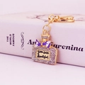 Elegant rhinestone perfume bottle keychain with purple bow on a white book background - Purple
