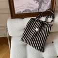 Detailed view of yellow and black striped canvas tote bag on a textured white sofa - Black and Yellow Vertical Stripes (Black Shoulder)