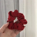 Dark red ribbed knit scrunchie hair tie held in hand with rich pleated texture - Artistic Girl China Red