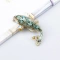 Fish resin figurine filled with turquoise gravel and gold leaf on a book edge - African Pine Stone
