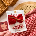 Detail showing a red knit bow hair clip and floral fabric snap clip on a paper card - Red Floral Bow & Knit Set 2Pcs