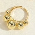 Detailaufnahme eines goldenen offenen Rings mit polierten Metallkugeln auf Lederstruktur - Fünf Kupferperlen Ring