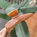 Caramel resin butterfly hair claw clip held in hand against green plant background - XL Butterfly Buckle (Approx. 13.5cm) / Sandalwood Orange