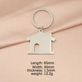 Llavero de acero inoxidable pulido con forma de casa sobre fondo de seda rosada - Plateado